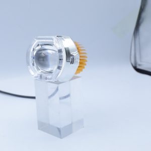 Small option angled view showing the clear lens shell, central projector, heat sink, and wire lead.